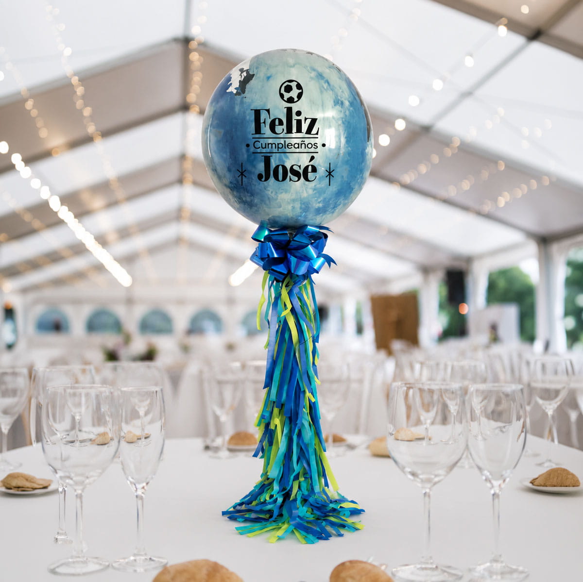 Centro de mesa para eventos con globo burbuja personalizado en tonos azules sobre mesa.